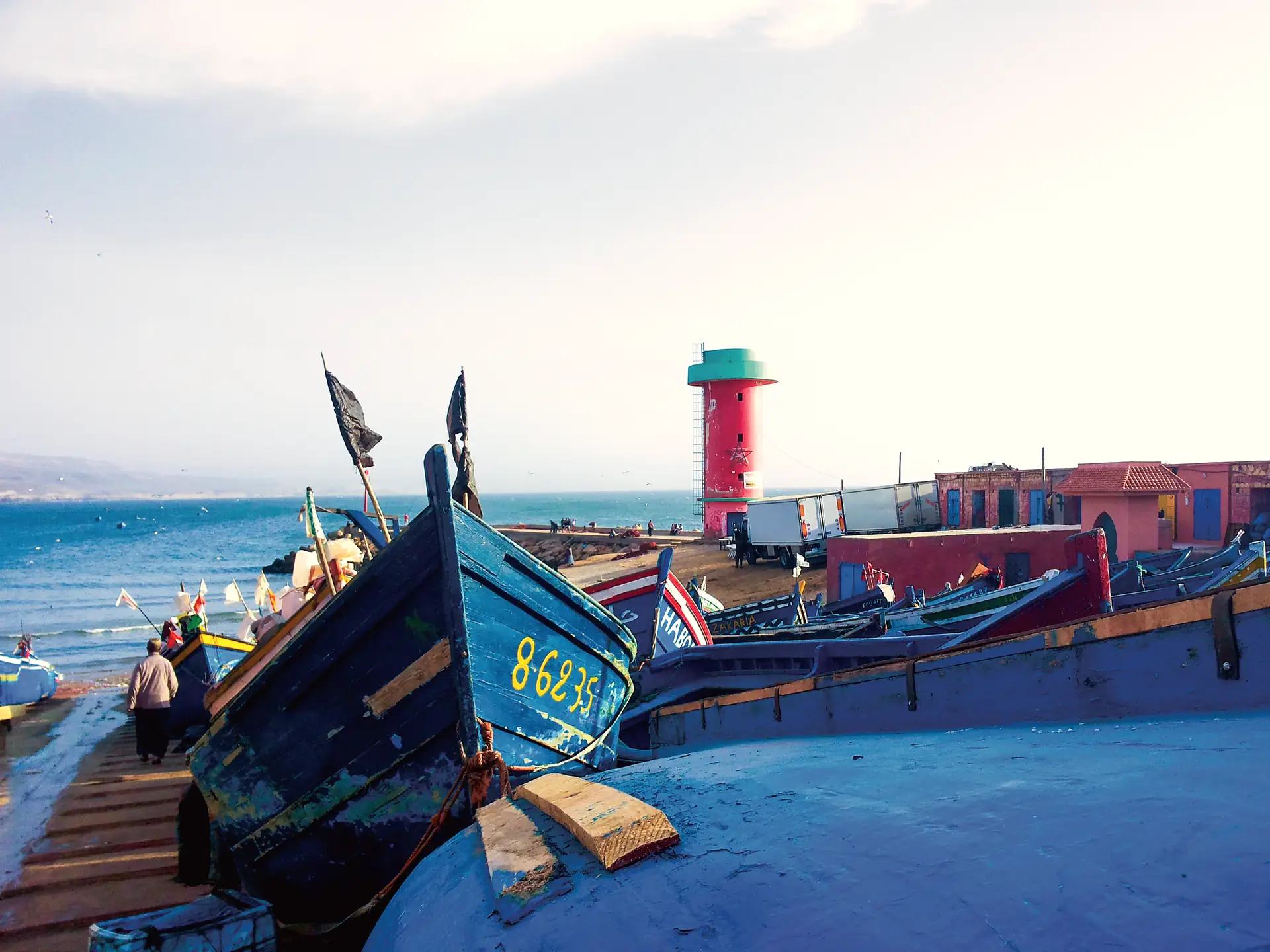 Blue fishing boats and the red lighthouse at Imsouane port