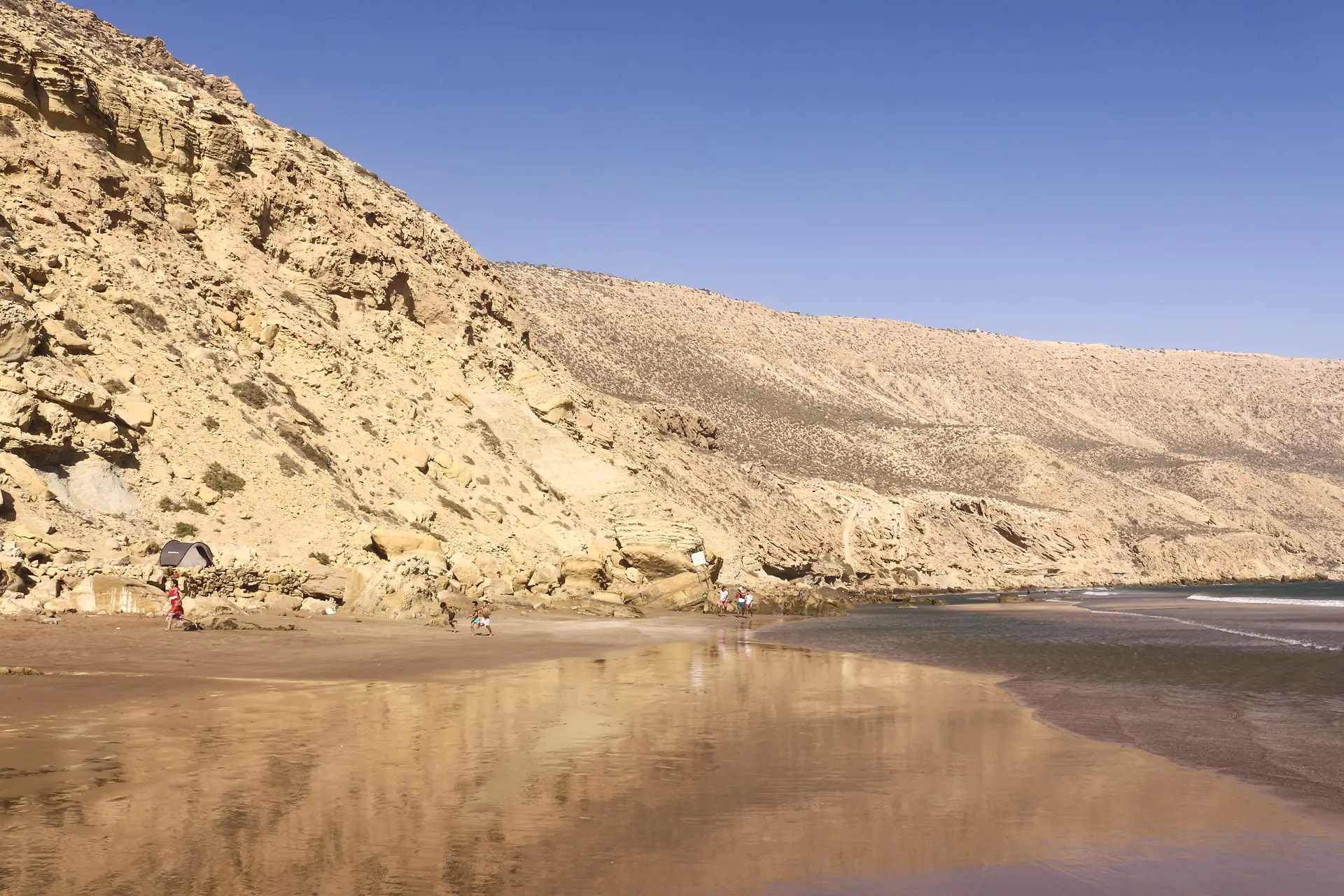 Ochre cliffs of Imsouane reflected in the wet sand at low tide